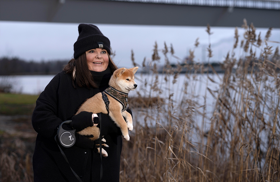 Nainen on shiba-koiran kanssa lumisessa maisemassa.